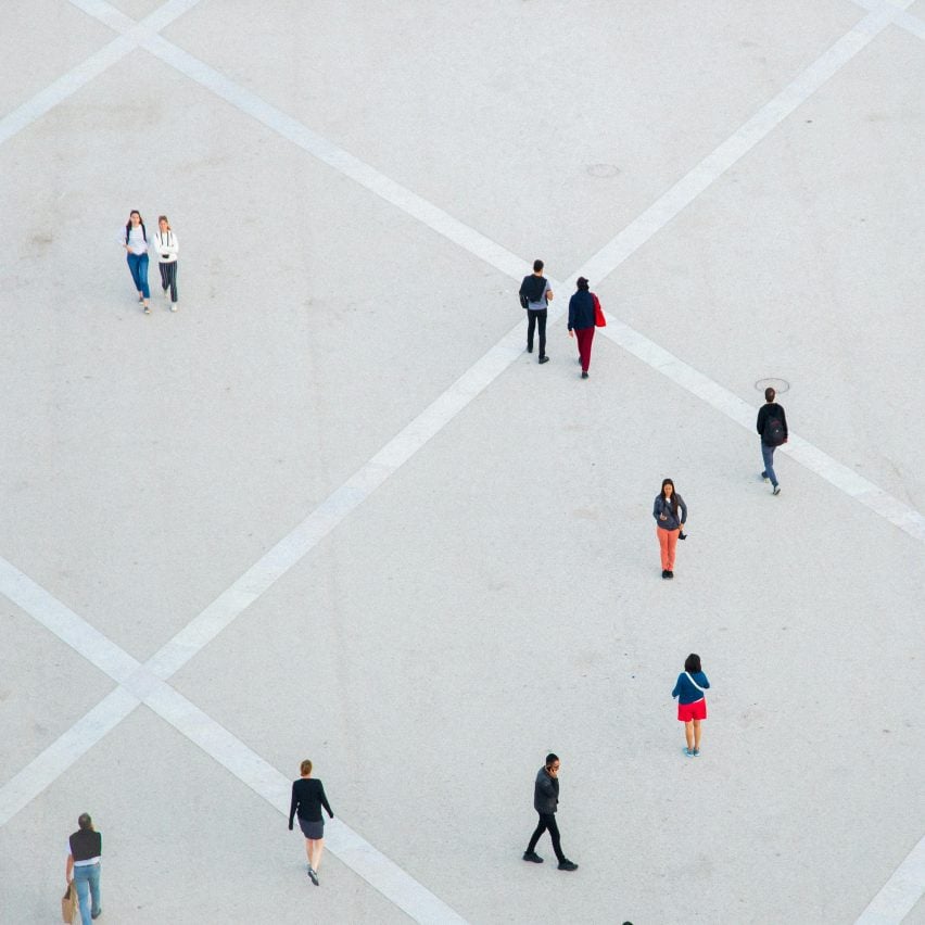 Aerial photo of people walking alone or in pairs or standing still in a vast concrete public space