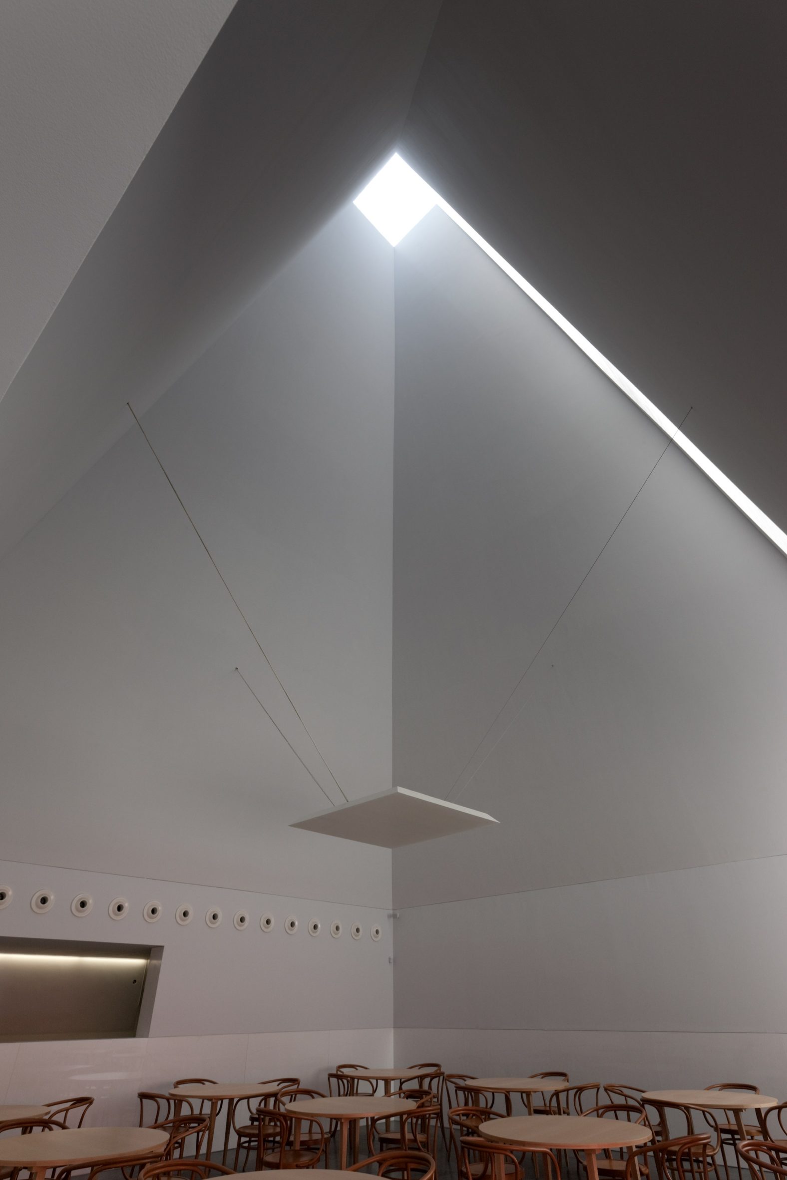 Tall gallery space with a pyramidal ceiling and overhead skylight bringing natural light into the room