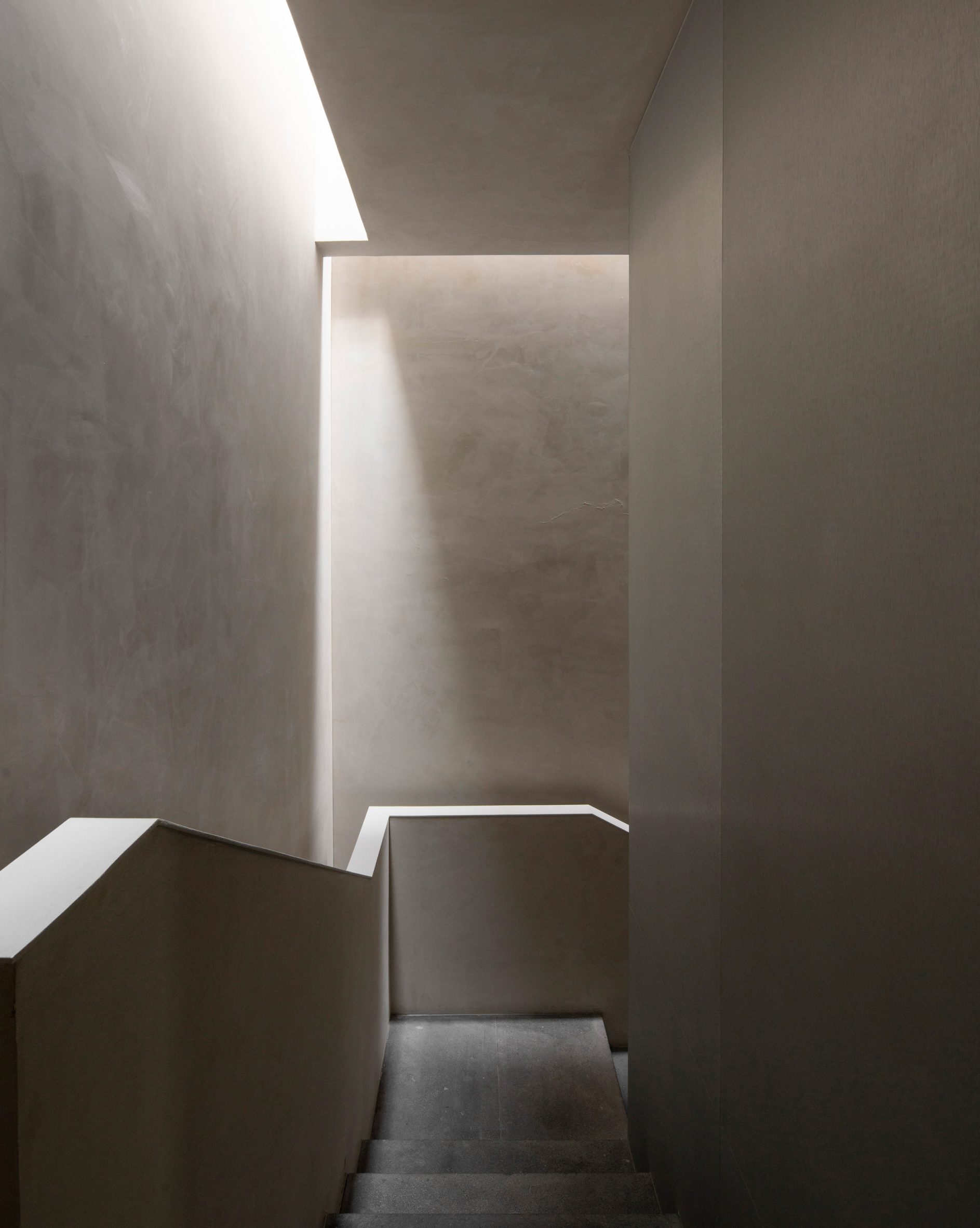 Shafts of light from a skylight dramatically illuminate a stairwell