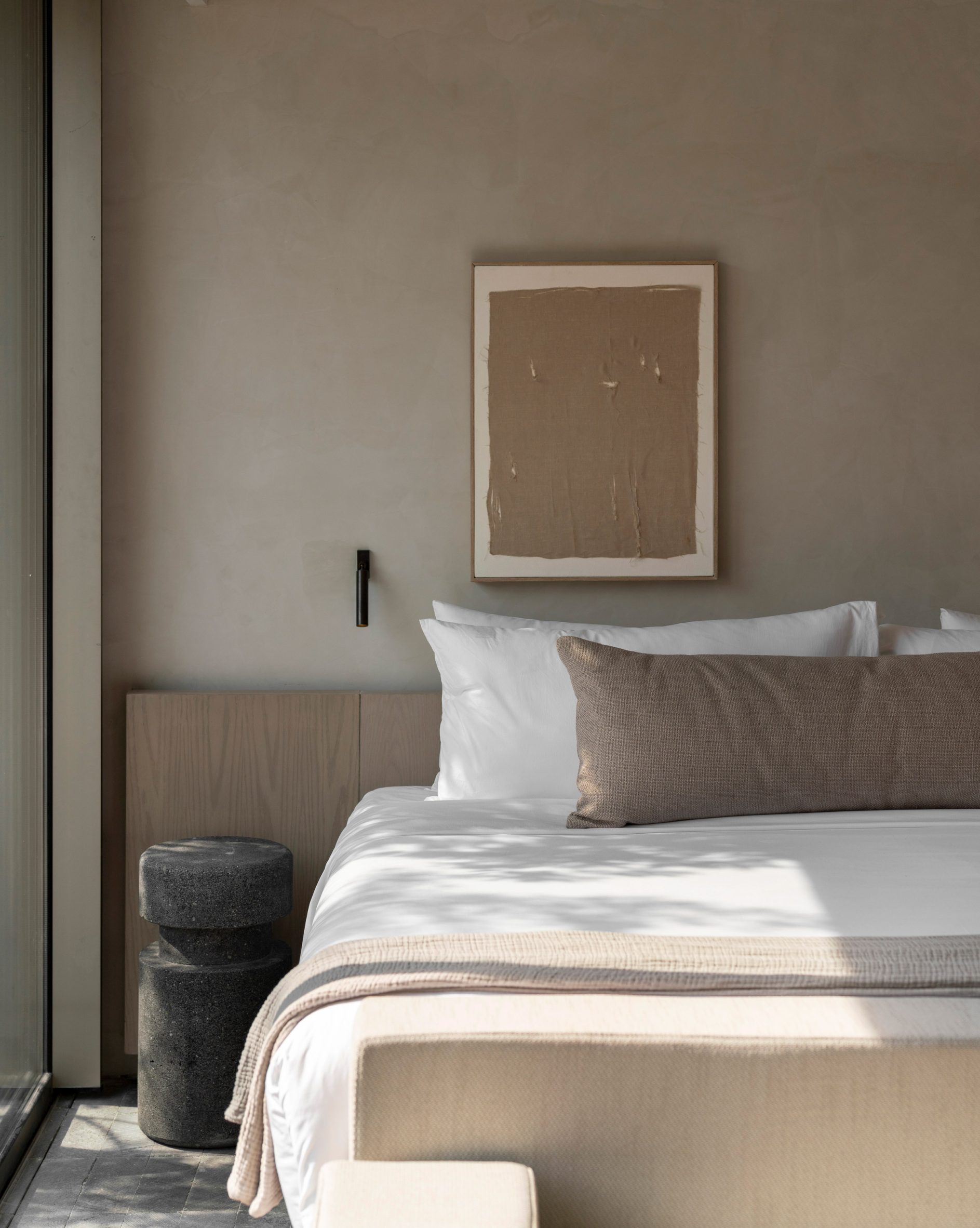 Guest room featuring volcanic stone flooring, pale wood furniture and beige plaster walls
